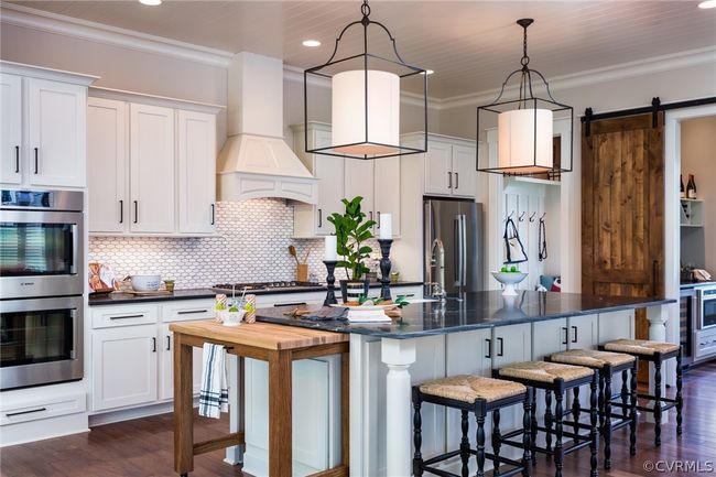 Kitchen featuring custom range hood, appliances with stainless steel finishes, an island with sink, dark hardwood / wood-style floors, and a barn door | Image 4