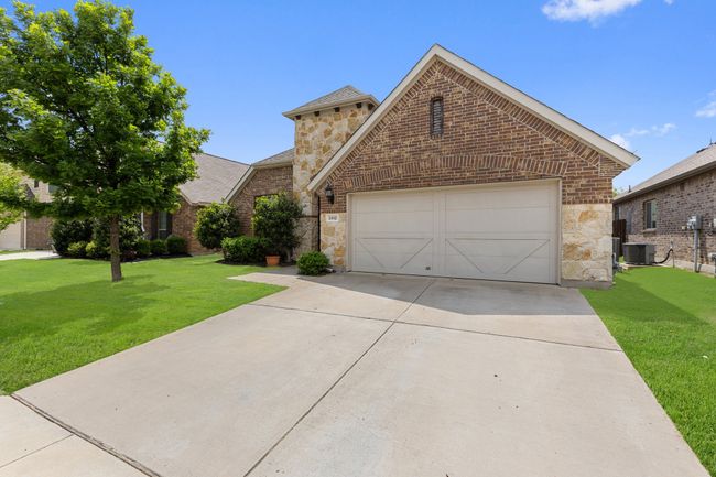 View of front of home featuring an attached garage, stone siding, a front yard, and concrete driveway | Image 5