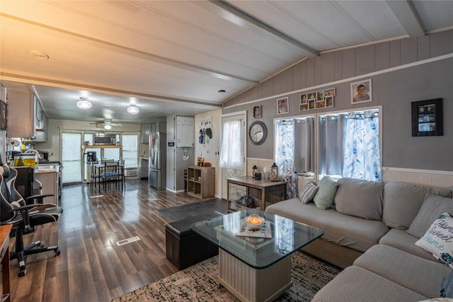 Living room featuring dark wood-style flooring, a ceiling fan, a wainscoted wall, and wooden walls | Image 8
