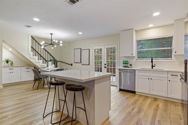Kitchen with light wood-style floors, tasteful backsplash, dishwasher, and a sink | Image 9