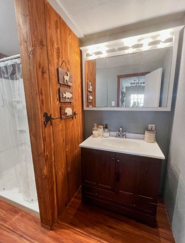 Bathroom featuring a stall shower, vanity, and wood finished floors | Image 8