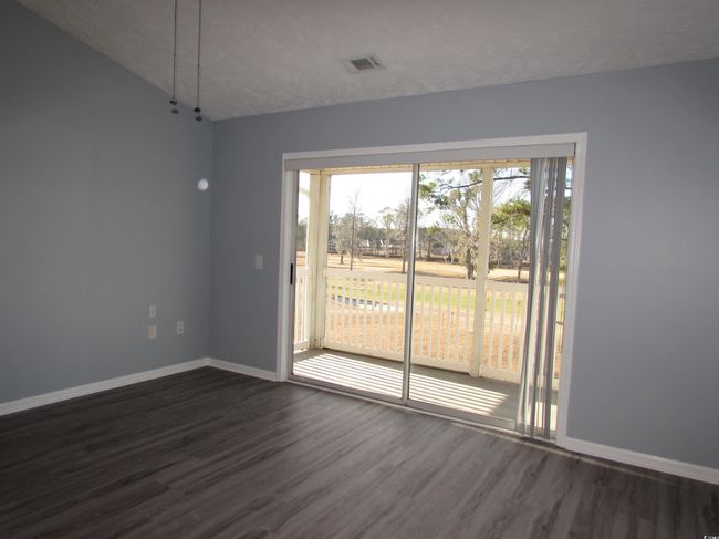 Living room with dark LVP flooring and sliding glass door to your screen porch. | Image 29
