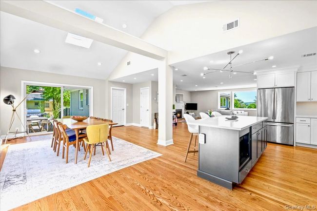 Kitchen with stainless steel fridge, vaulted ceiling, light wood-type flooring, white cabinetry, and light countertops | Image 8