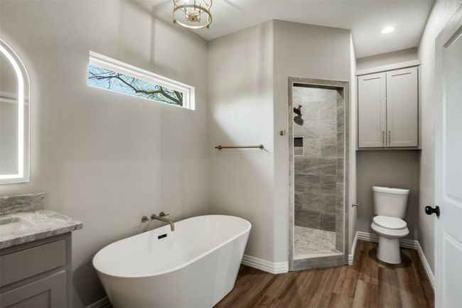 Full bath with a freestanding bath, toilet, a stall shower, wood finished floors, and vanity | Image 15