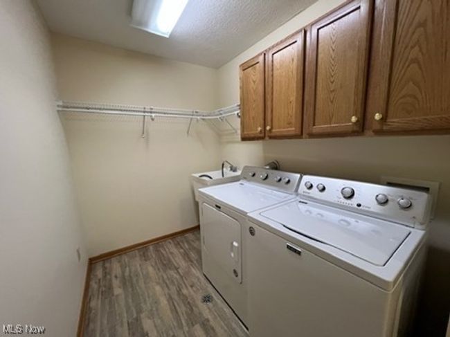 Laundry area with cabinet space, separate washer and dryer, and wood finished floors | Image 26