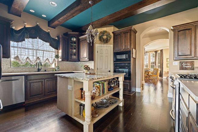 Kitchen featuring open shelves, stainless steel appliances, arched walkways, wood finished floors, and beam ceiling | Image 12