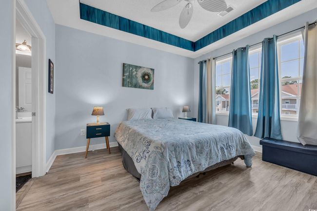 Bedroom with visible vents, connected bathroom, light wood-type flooring, baseboards, and ceiling fan | Image 18