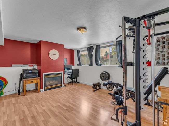 Exercise area featuring baseboards, wood finished floors, a glass covered fireplace, and a textured ceiling | Image 18