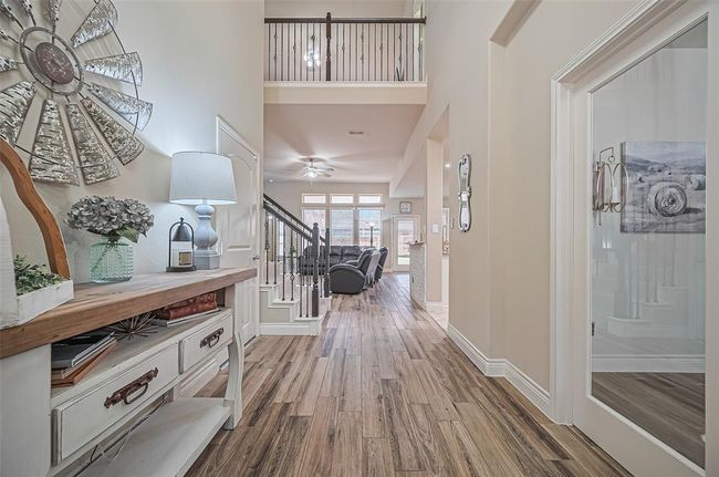 Upon entering, you are greeted with updated tile flooring, styled to mimic hardwood, that flows seamlessly through the main level—paired with soaring ceilings and curated paint selections to create an inviting and elevated atmosphere. | Image 4