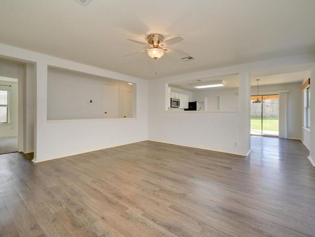 View of living room from the front door with luxury vinyl wood look flooring and a ceiling fan. | Image 4