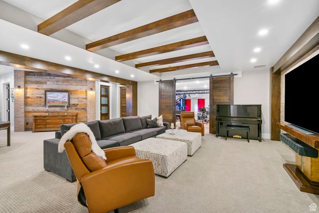 Carpeted living room featuring beamed ceiling, visible vents, recessed lighting, a barn door, and wood walls | Image 79
