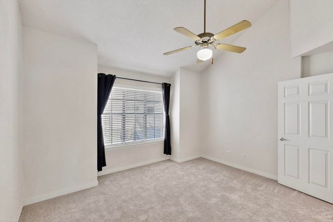 Unfurnished bedroom featuring light carpet, lofted ceiling, and a ceiling fan | Image 24