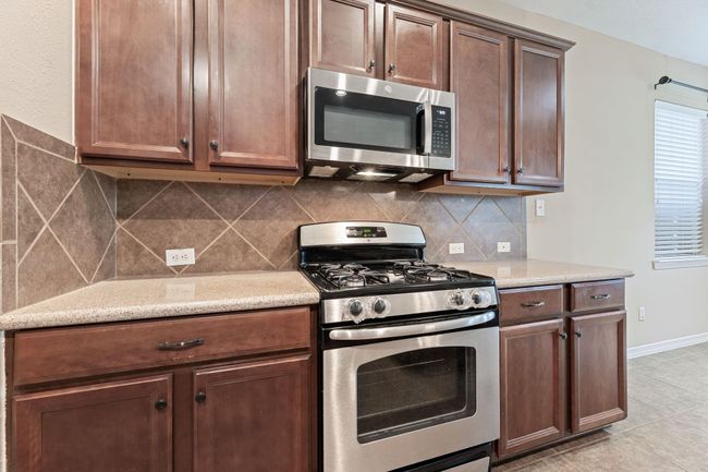 Open kitchen area with stainless appliances allows for easy flow of traffic, perfect for those busy mornings! | Image 18
