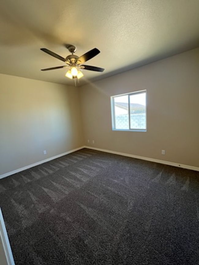 Empty room featuring baseboards, dark colored carpet, and ceiling fan | Image 19