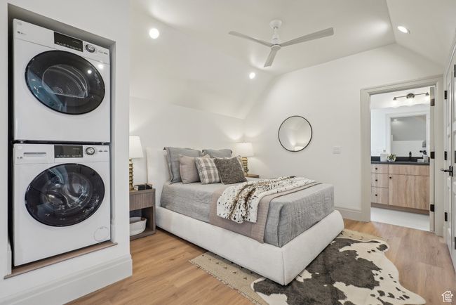 Bedroom featuring lofted ceiling, stacked washer and dryer, ceiling fan, and light wood-style floors | Image 36