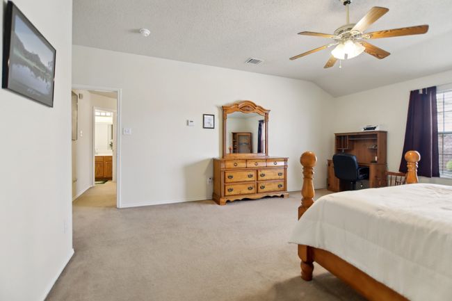 Carpeted bedroom featuring a textured ceiling, visible vents, baseboards, ceiling fan, and vaulted ceiling | Image 19