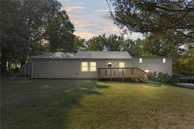 Front of house at dusk with a wooden deck and lawn | Image 2