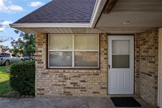 Doorway to property with a shingled roof and brick siding | Image 10
