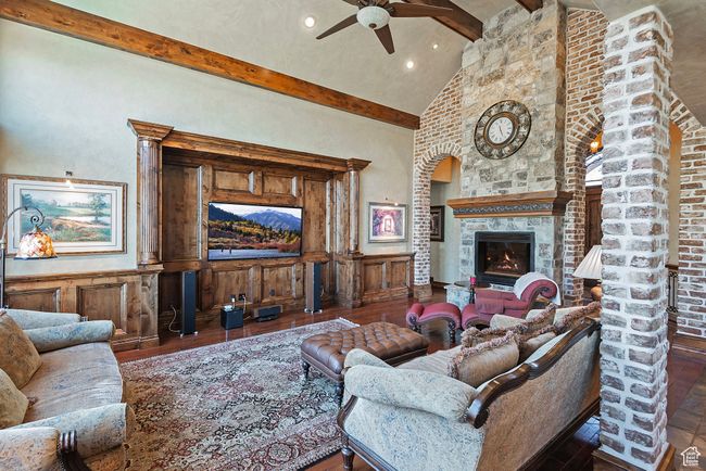 Living area featuring a ceiling fan, beamed ceiling, high vaulted ceiling, hardwood / wood-style floors, and a glass covered fireplace | Image 16