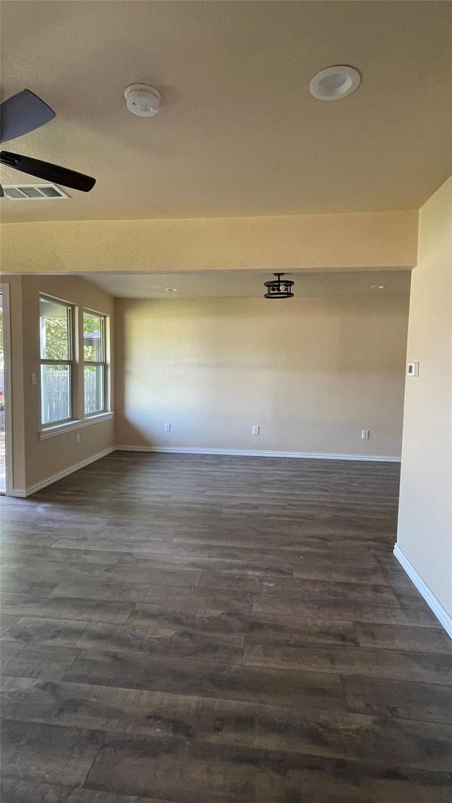 Spare room with visible vents, baseboards, dark wood-type flooring, and a ceiling fan | Image 6