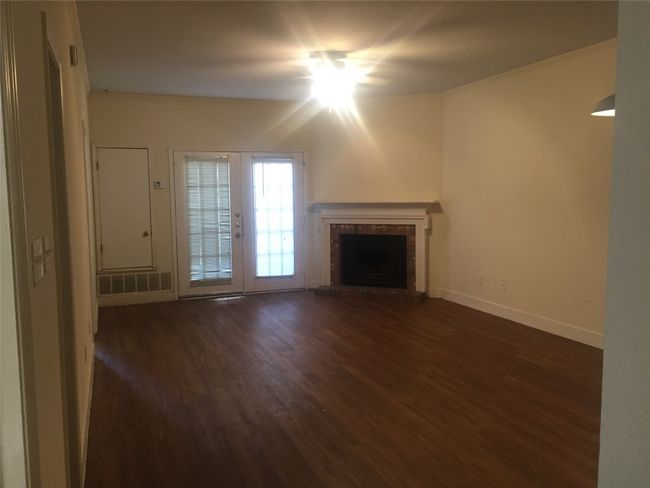 Unfurnished living room with baseboards, visible vents, a brick fireplace, and dark wood-style floors | Image 17