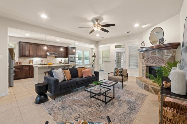 Living area with light tile patterned floors, ceiling fan, a fireplace, and recessed lighting | Image 5
