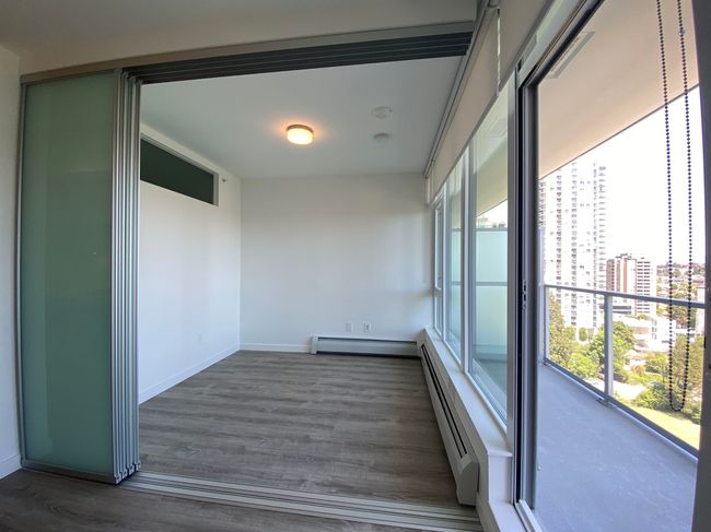 Unfurnished room with baseboards, baseboard heating, wood finished floors, and a view of city | Image 9