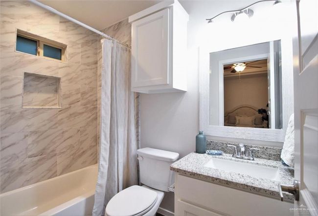 Full bath featuring vanity, shower / tub combo with curtain, and ceiling fan | Image 4