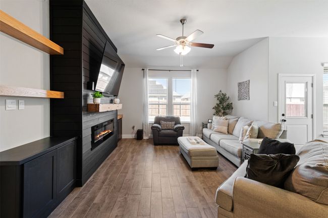 Living area featuring lofted ceiling, light wood finished floors, a large fireplace, and a ceiling fan | Image 17