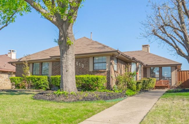 View of front of home featuring brick siding and nice landscaping complete with sprinkler system. | Image 4