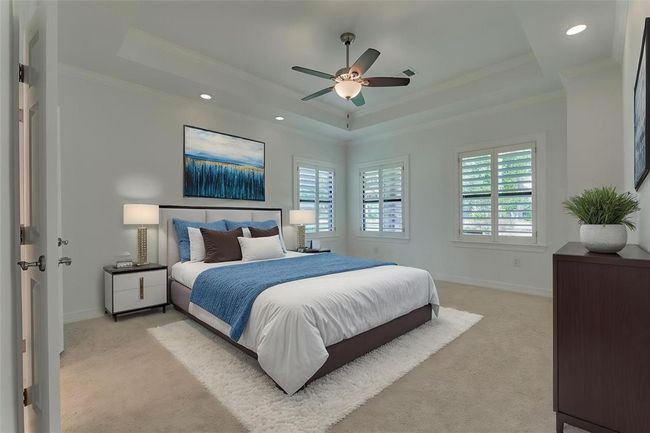 The second primary bedroom is generously sized and features windows overlooking the front yard, dressed with custom shutters for added privacy and charm. Dimmable lighting on either side of the room offers versatile ambiance, while a tray ceiling enhances the sense of space and openness. Photo has been virtually staged to show furniture placement. | Image 27